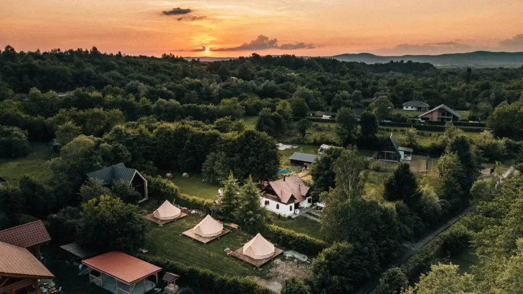 Vedere aeriană a unui glamping cu corturi tip clopot, la apus, în România