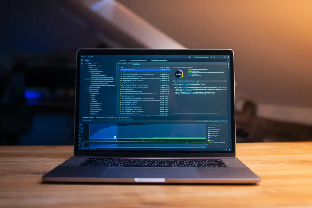 Acasă (v2) Laptop pe un birou din lemn, cu grafice și date tehnice deschise pe ecran